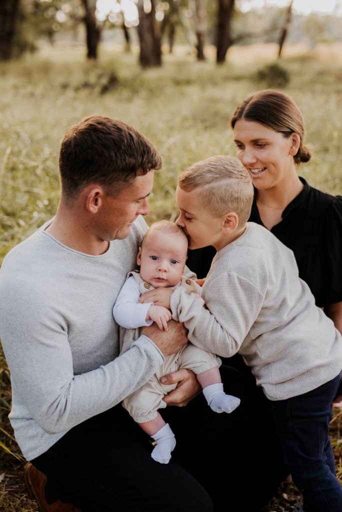 Baby with sagittal synostosis held by family outdoors