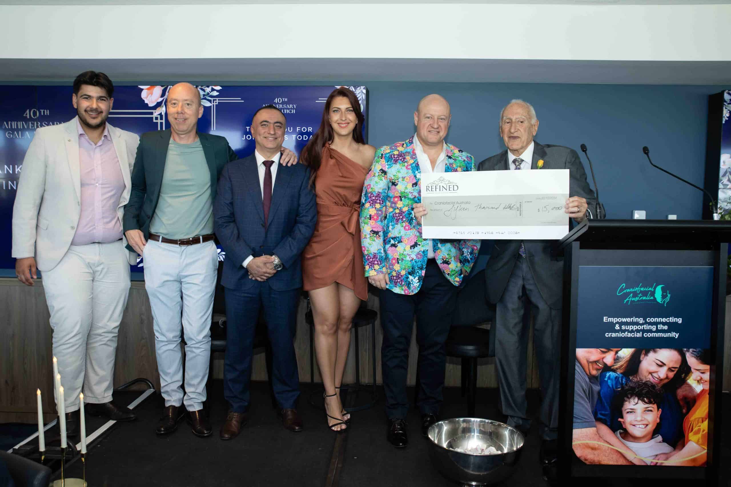 Craniofacial Australia partners at an event, holding a large cheque for fundraising and support.
