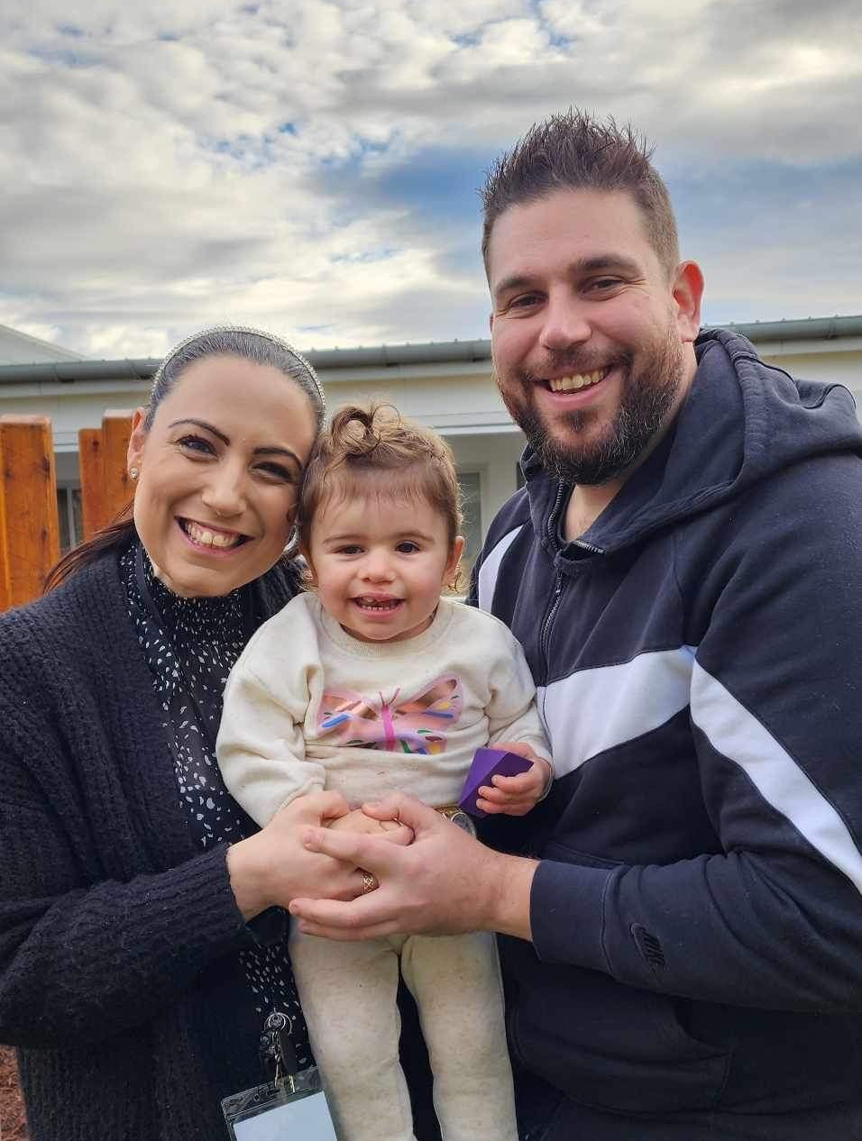 Craniofacial family with young girl, smiling outdoors, promoting craniofacial care and support.