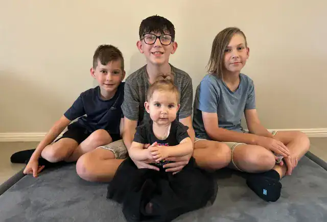Little girl with sagittal synostosis sitting surrounded by her siblings