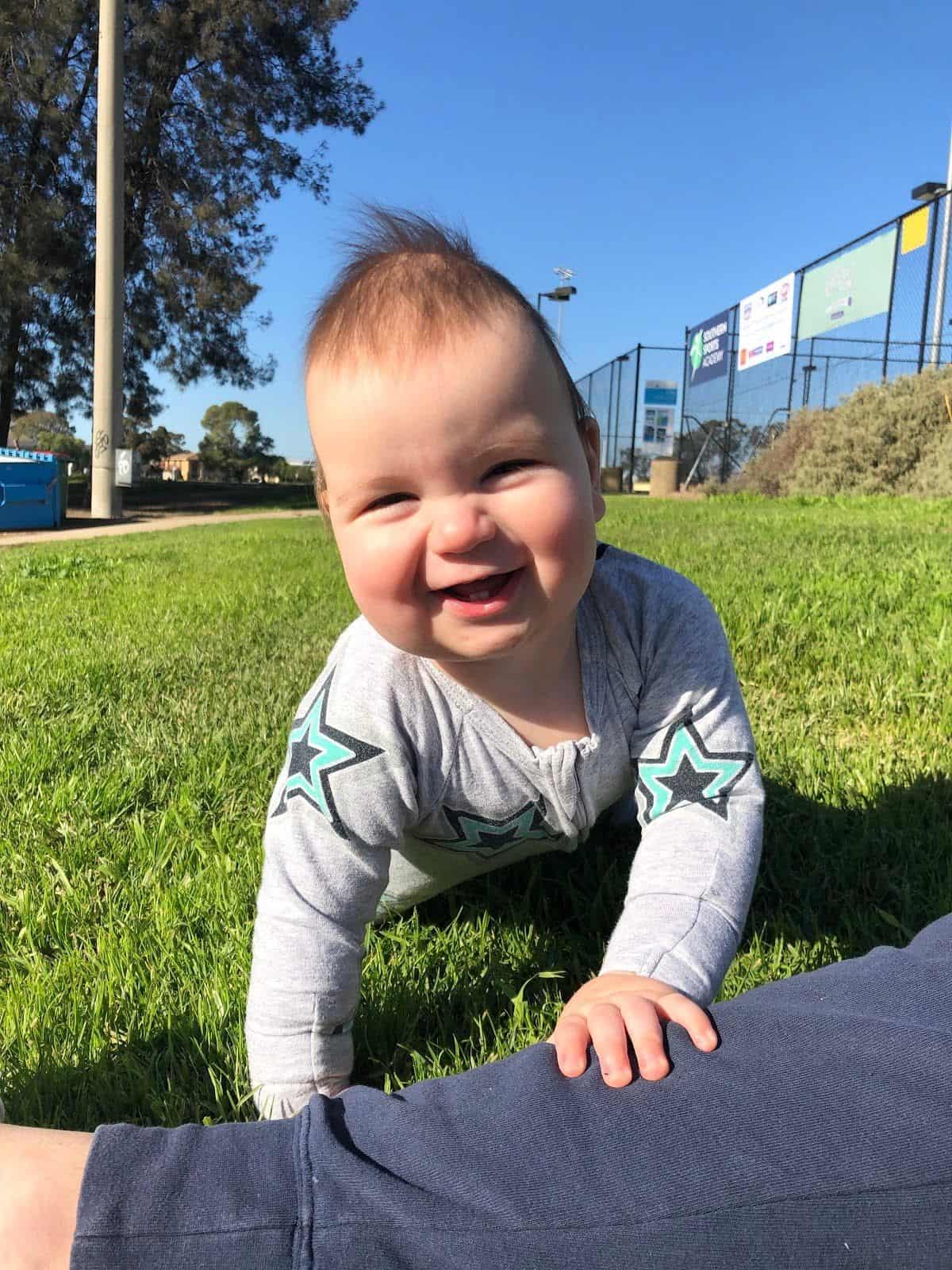 Baby with sagittal synostosis, pre-surgery, crawling on grass.