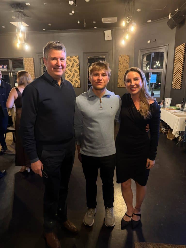 Craniofacial Australia event with smiling professionals and young man in a social setting.