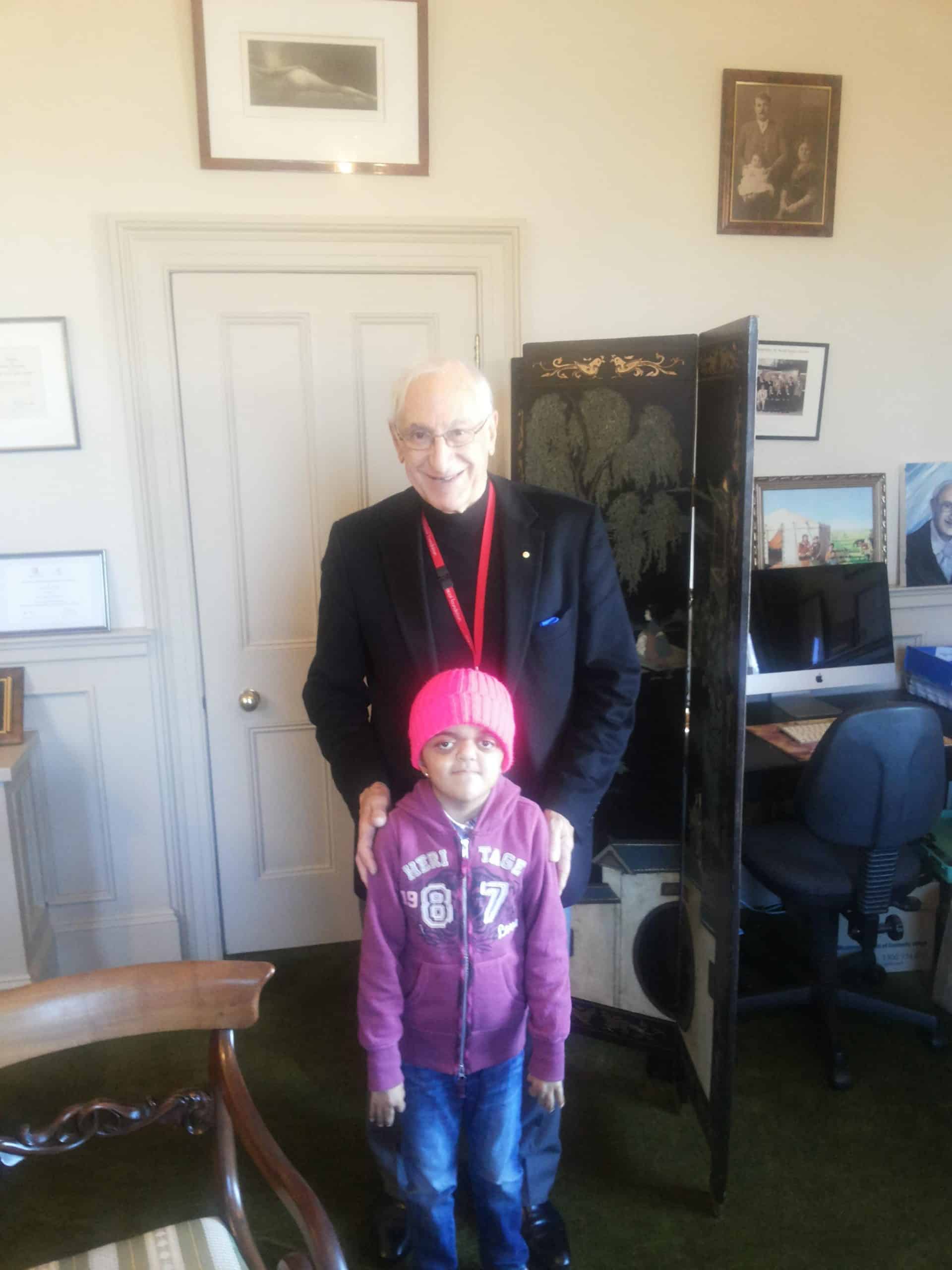 Smiling elderly man with a young girl in a medical office setting.